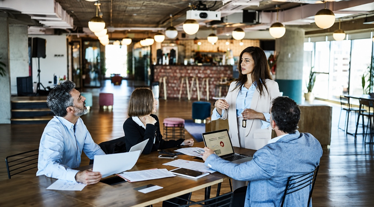 Team meeting in a modern coworking space with professionals discussing ideas around a conference table.